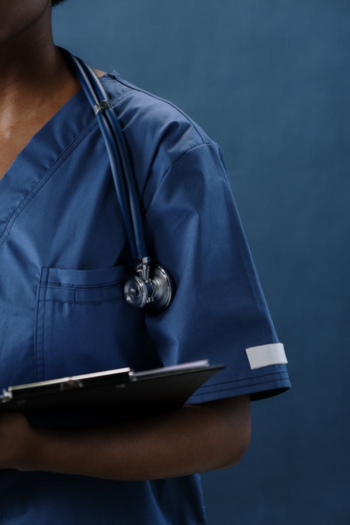 our-story-01 Close-up of a healthcare professional in blue scrubs with a stethoscope and clipboard.