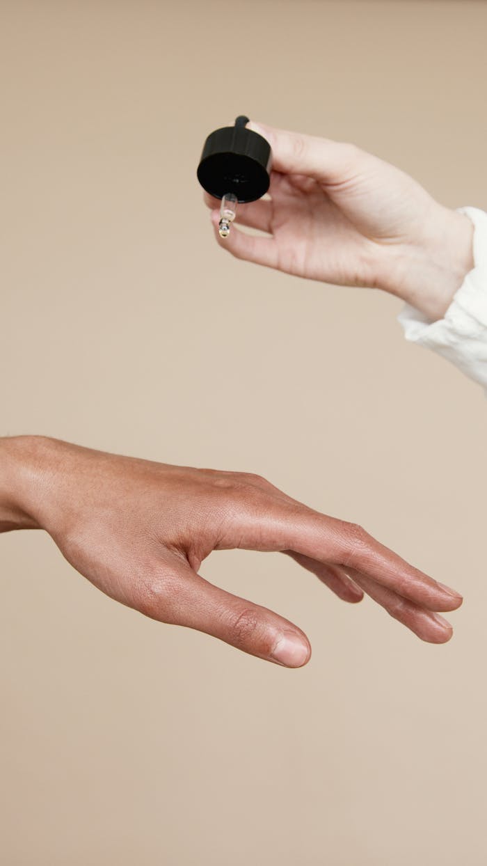 why-choose-us-02 Two hands applying skin care oil with a dropper. Ideal for wellness and beauty themes.